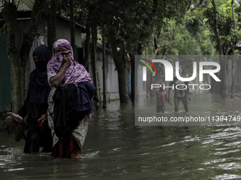 Women are walking past a street submerged by flood water in Jamalpur, Bangladesh, on July 9, 2024. (