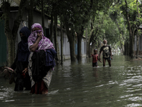 Women are walking past a street submerged by flood water in Jamalpur, Bangladesh, on July 9, 2024. (