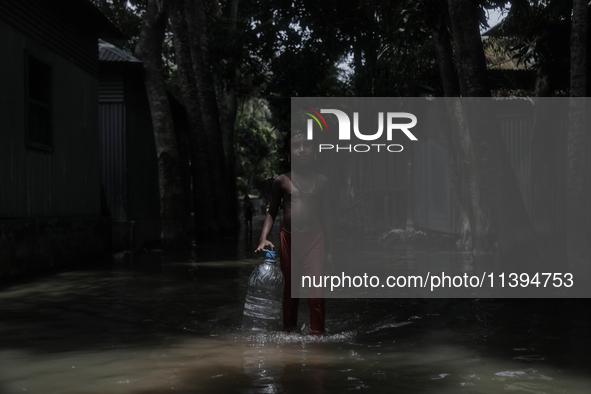 Shamima Parveen (8) is walking past a street submerged by flood water to collect fresh drinking water in Jamalpur, Bangladesh, on July 9, 20...