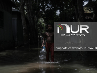 Shamima Parveen (8) is walking past a street submerged by flood water to collect fresh drinking water in Jamalpur, Bangladesh, on July 9, 20...