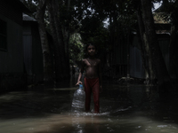 Shamima Parveen (8) is walking past a street submerged by flood water to collect fresh drinking water in Jamalpur, Bangladesh, on July 9, 20...