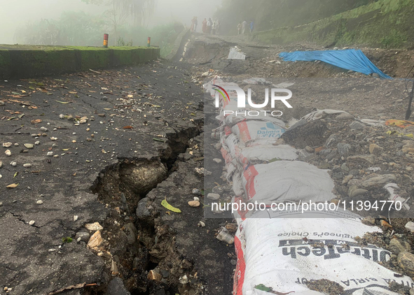 Local villagers are standing near the damaged portions of the national highway 55 due to continuous rainfall and landslides, on the route of...