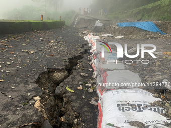 Local villagers are standing near the damaged portions of the national highway 55 due to continuous rainfall and landslides, on the route of...