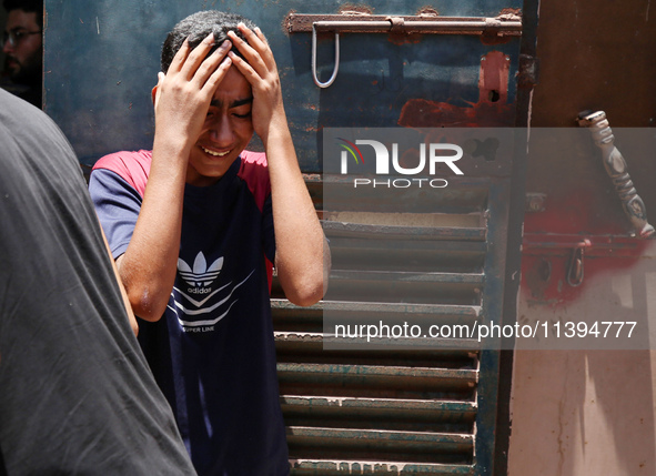 People are crying near the bodies of Palestinians killed in Israeli strikes, amid the Israel-Hamas conflict, at Al-Aqsa Martyrs Hospital in...