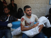 A Palestinian father is carrying the body of his son who was killed in an Israeli strike, amid the Israel-Hamas conflict, at Al-Aqsa Martyrs...