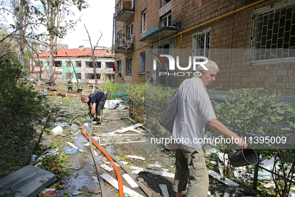 Rescuers and a man are being pictured at a five-storey apartment block in the Holosiivskyi district destroyed by the Russian missile attack...