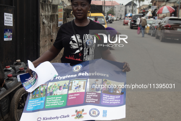 A woman is holding a poster as members of the Ministry of Environment in Lagos are embarking on a door-to-door campaign to sensitize the cit...