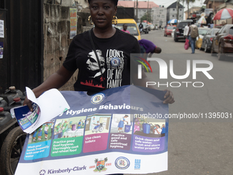 A woman is holding a poster as members of the Ministry of Environment in Lagos are embarking on a door-to-door campaign to sensitize the cit...