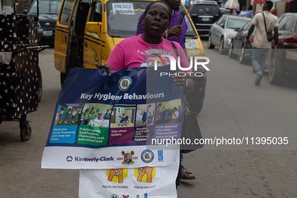 A woman is holding a poster as members of the Ministry of Environment in Lagos are embarking on a door-to-door campaign to sensitize the cit...