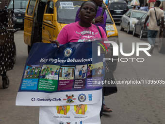 A woman is holding a poster as members of the Ministry of Environment in Lagos are embarking on a door-to-door campaign to sensitize the cit...