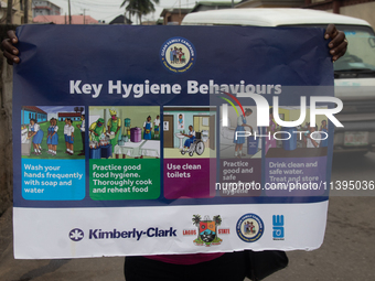 A woman is holding a poster as members of the Ministry of Environment in Lagos are embarking on a door-to-door campaign to sensitize the cit...