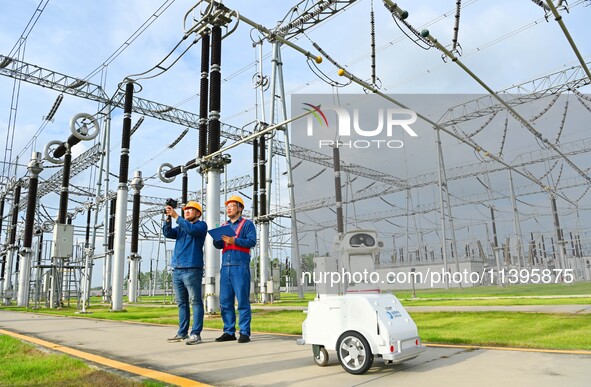 A 5G intelligent robot and operation and maintenance personnel are carrying out a special inspection of the power supply equipment in a 500-...