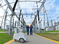 A 5G intelligent robot and operation and maintenance personnel are carrying out a special inspection of the power supply equipment in a 500-...