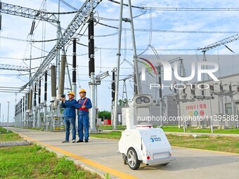 A 5G intelligent robot and operation and maintenance personnel are carrying out a special inspection of the power supply equipment in a 500-...