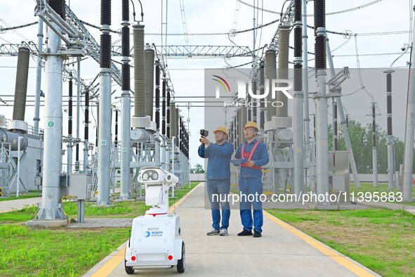 A 5G intelligent robot and operation and maintenance personnel are carrying out a special inspection of the power supply equipment in a 500-...