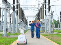 A 5G intelligent robot and operation and maintenance personnel are carrying out a special inspection of the power supply equipment in a 500-...