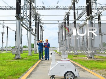 A 5G intelligent robot and operation and maintenance personnel are carrying out a special inspection of the power supply equipment in a 500-...