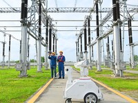 A 5G intelligent robot and operation and maintenance personnel are carrying out a special inspection of the power supply equipment in a 500-...