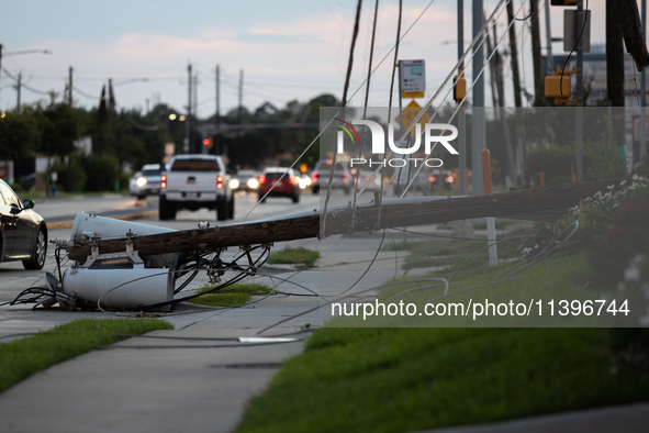 Cars are passing a fallen power line on Memorial Drive in Houston, Texas, on July 9, 2024, following Hurricane Beryl. 