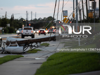 Cars are passing a fallen power line on Memorial Drive in Houston, Texas, on July 9, 2024, following Hurricane Beryl. (