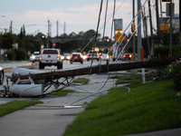 Cars are passing a fallen power line on Memorial Drive in Houston, Texas, on July 9, 2024, following Hurricane Beryl. (