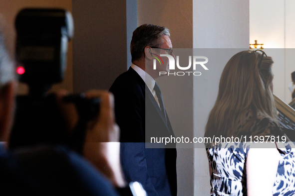 Partially illuminated by a camera flash, Keir Starmer, Prime Minister of the United Kingdom, departs a meeting between a bipartisan group of...