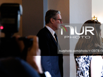 Partially illuminated by a camera flash, Keir Starmer, Prime Minister of the United Kingdom, departs a meeting between a bipartisan group of...