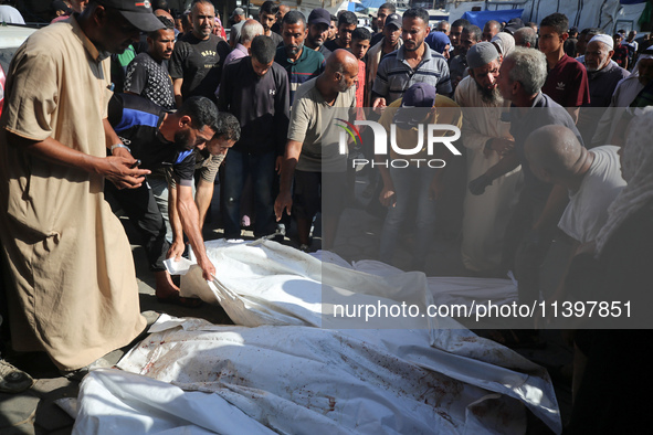 Mourners are praying next to the body of a Palestinian killed in an Israeli strike, amid the Israel-Hamas conflict, in Deir el-Balah, Gaza S...