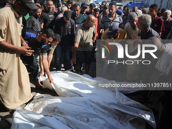 Mourners are praying next to the body of a Palestinian killed in an Israeli strike, amid the Israel-Hamas conflict, in Deir el-Balah, Gaza S...