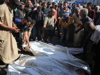 Mourners are praying next to the body of a Palestinian killed in an Israeli strike, amid the Israel-Hamas conflict, in Deir el-Balah, Gaza S...