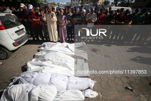 Mourners are praying next to the body of a Palestinian killed in an Israeli strike, amid the Israel-Hamas conflict, in Deir el-Balah, Gaza S...