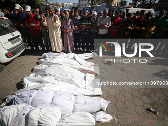 Mourners are praying next to the body of a Palestinian killed in an Israeli strike, amid the Israel-Hamas conflict, in Deir el-Balah, Gaza S...