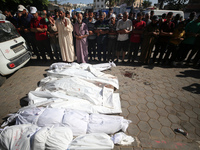 Mourners are praying next to the body of a Palestinian killed in an Israeli strike, amid the Israel-Hamas conflict, in Deir el-Balah, Gaza S...