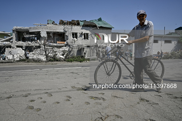 An elderly man is pushing a bicycle past a building damaged by the July 8 Russian missile attack in Vilniansk, Zaporizhzhia region, southeas...