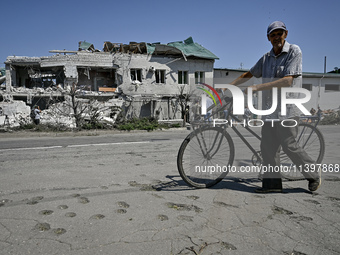 An elderly man is pushing a bicycle past a building damaged by the July 8 Russian missile attack in Vilniansk, Zaporizhzhia region, southeas...