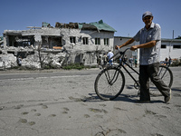 An elderly man is pushing a bicycle past a building damaged by the July 8 Russian missile attack in Vilniansk, Zaporizhzhia region, southeas...