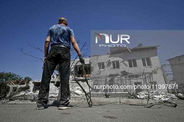 A man is holding a metal wire and looking at a building damaged by the July 8 Russian missile attack in Vilniansk, Zaporizhzhia region, sout...