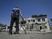 A man is holding a metal wire and looking at a building damaged by the July 8 Russian missile attack in Vilniansk, Zaporizhzhia region, sout...