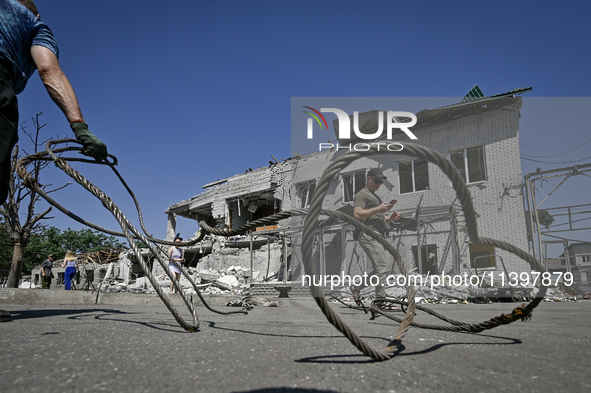 A man is holding a metal wire and looking at a building damaged by the July 8 Russian missile attack in Vilniansk, Zaporizhzhia region, sout...