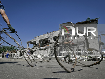 A man is holding a metal wire and looking at a building damaged by the July 8 Russian missile attack in Vilniansk, Zaporizhzhia region, sout...