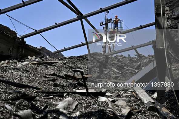 A utility worker is looking at a hangar with agricultural products damaged by the July 8 Russian missile attack in Vilniansk, Zaporizhzhia r...