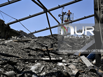 A utility worker is looking at a hangar with agricultural products damaged by the July 8 Russian missile attack in Vilniansk, Zaporizhzhia r...