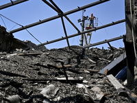 A utility worker is looking at a hangar with agricultural products damaged by the July 8 Russian missile attack in Vilniansk, Zaporizhzhia r...