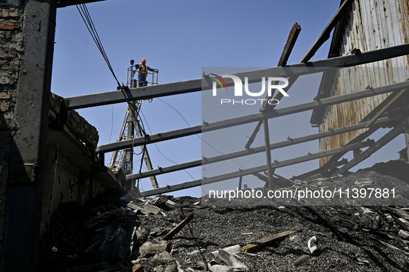 A utility worker is looking at a hangar with agricultural products damaged by the July 8 Russian missile attack in Vilniansk, Zaporizhzhia r...