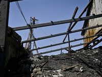 A utility worker is looking at a hangar with agricultural products damaged by the July 8 Russian missile attack in Vilniansk, Zaporizhzhia r...