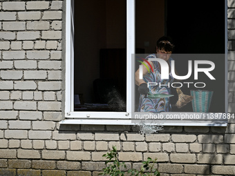 A woman is throwing away glass shards from a building damaged by the July 8 Russian missile attack in Vilniansk, Ukraine, on July 9, 2024. N...