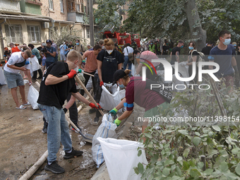 Locals are helping remove the rubble at a section of a five-storey apartment building in the Shevchenkivskyi district destroyed by the Russi...