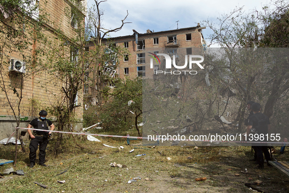 Police officers are staying near a section of a five-storey apartment block in the Shevchenkivskyi district destroyed by the Russian missile...