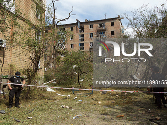 Police officers are staying near a section of a five-storey apartment block in the Shevchenkivskyi district destroyed by the Russian missile...