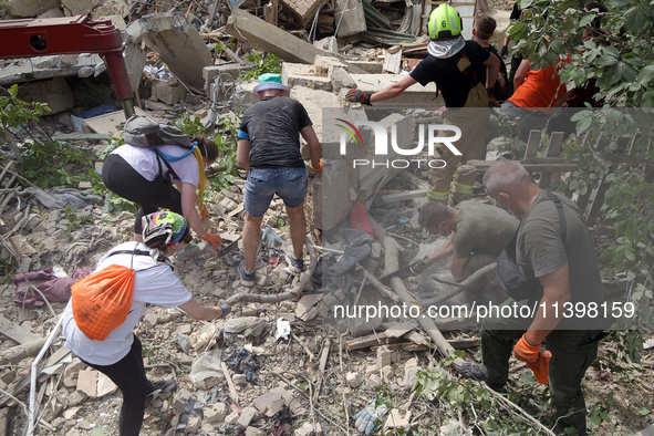 Locals are helping remove the rubble at a section of a five-storey apartment building in the Shevchenkivskyi district destroyed by the Russi...